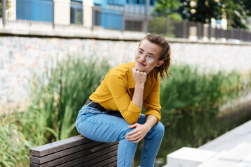 Young woman relaxing on a low wall in town
