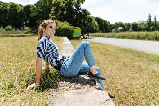 Young woman relaxing on a rural retaining wall
