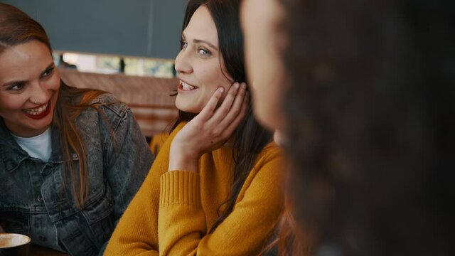 Diverse group of women friends gossiping at a cafe. Happy young females sitting in a coffee shop and talking.
