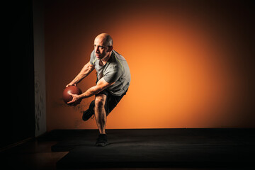 Middle aged male athlete training with medicine ball.