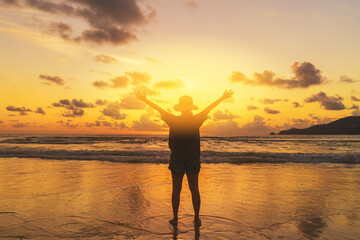 Happy woman raise hand up at tropical beach with sunset sky background. Travel vacation and freedom feel good concept.