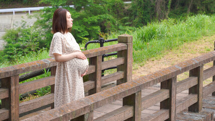 橋の上に立つ若い妊婦さん