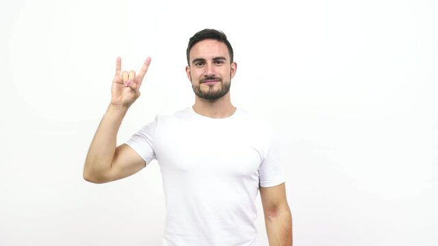 Young caucasian man doing a rock gesture, enjoying life and laughing