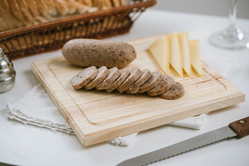 Queso de cerdo codeguín en tabla de madera con quesos y pan, acompañado de vino blanco