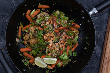 Vegan carrot, broccoli and cauliflower stir fry with nuts and seeds, black wok