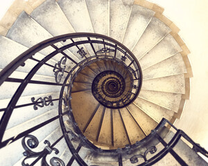 Round spiral staircase with gray walls black railings with patterns down view