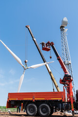 Construction of a wind power plant. Installers use a truck crane and aerial platform to raise the...
