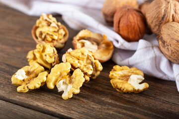 Walnut kernels and whole walnuts on rustic old wooden table. Fresh walnuts on wooden board.