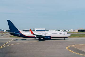 Fototapeta premium Side view of modern lowcost boeing waiting for take-off permit in airport terminal, international commercial vehicle parking during voyage check in, jet airliner for passengers transportation