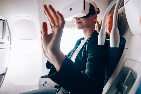 Excited woman enjoying VR goggles device in airplane