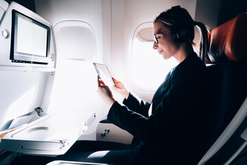 Cheerful female freelancer watching video on tablet during flight