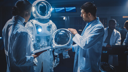 Diverse Team of Aerospace Scientists and Engineers Wearing White Coats have Discussion, Use Computers, Construct Astronaut Helmet for New Space Suit Adapted for Galaxy Exploration and Travel. © Gorodenkoff