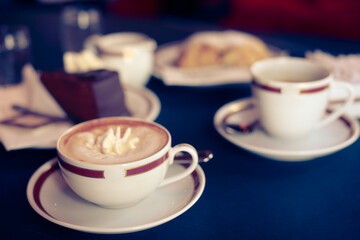 Coffee with cream in cap and with chocolate cake on table in cafe