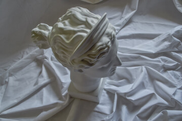 Ancient greek sculpture white plaster marble head of diana on a background of white fabric drapery with folds