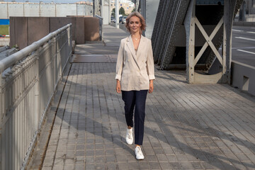 young woman in business walks across the city bridge