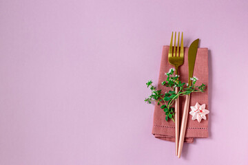 Knife and fork and linen napkin on pink background. Holiday celebration.