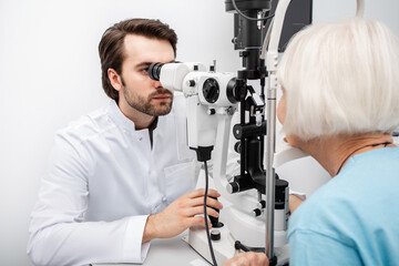 Optometrist checking vision to an old patient using a slit lamp. Eye exam patient with cataract