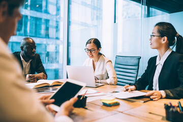 Caucasian secretary reading web notes during corporate meeting of executive bosses, group of successful male and female employers discussing trade exchange sharing informative experience in office