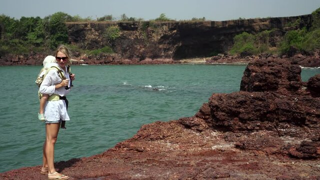 Woman tourist carries a baby on her back using an ergo backpack