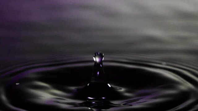 Drop falls into water and diverging circles of water on white background in slow motion