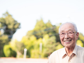 An elderly Asian man smiling happily outside
