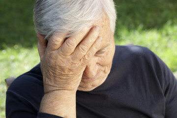 Senior caucasian woman holds her hand to her forehead. Headache, depression or Alzheimer's disease symptoms.