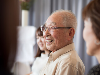 A very old asian man talking happily while surrounded by his family - 375893338
