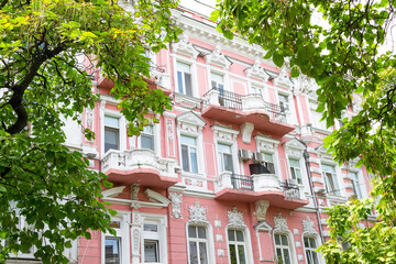 Facade of old pink architecture building with balconies and sculptures in sunny day, city trip