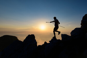 Athlete skyrunner in silhouette on the downhill rocks