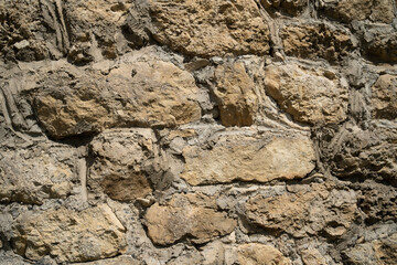 Texture of old stones of various forms with seams. Close up of shabby masonry. Stone wall from uneven different ancient friable cobblestones.