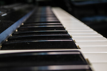 Piano keyboard keys of synth close up view. Shot of a black and white keys of a musical instrument with dust are pressed.