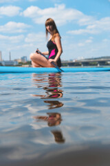 Beautiful millennial woman on a SUP board on the river. Active rest concept. Blurred person and copy space.