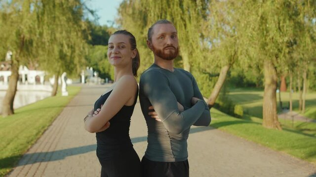 Funny happy fitness woman and man in the park after training jogging look at camera smile at sunlight trainer done instructor activity active working out energy sportswoman portrait slow motion