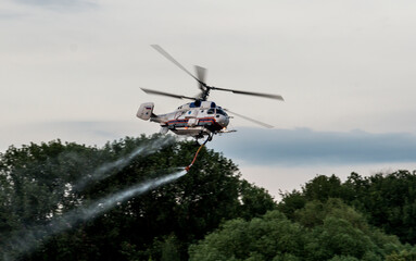 Fototapeta na wymiar Fire helicopter draws water from the lake