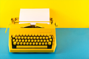 Yellow bright typewriter on a yellow and blue background. Symbol for writing, blogging, new ideas...