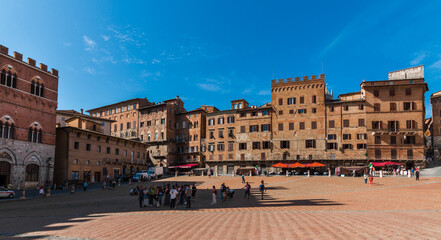 Gorgeous panorama image of various palazzi signorili at the famous Palazzo Pubblico (town hall) surrounding the Piazza del Campo on a sunny day with a blue sky in Siena, Tuscany, Italy.