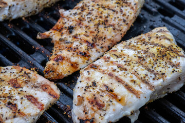 Lemon pepper chicken breasts cooking on a grill
