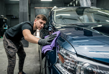 Obraz na płótnie Canvas man holds the microfiber in hand and polishes the car