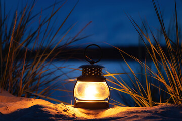 Burning candle lantern on the beach. Sea and night sky on background. Candle light. 
