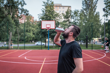 man drinking water on a public sports ground