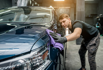 man holds the microfiber in hand and polishes the car