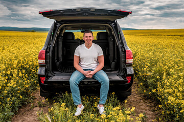 smiled young man sitting in the trunk of a car
