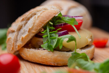 Home made hamburger with beef, onion, tomato, lettuce and cheese. Fresh burger closeup on wooden rustic table with fresh vegetables. Cheeseburger.