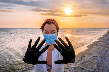 woman in rubber gloves and medical mask on the beach