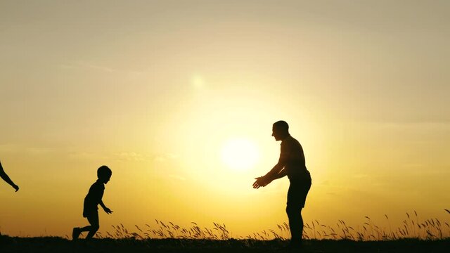 A little boy runs to his father. A happy father throws the child up, playing and kissing it. The concept of a happy family, kinship and care. Silhouette. teamwork
