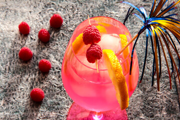 Raspberry drink in a glass with berries and lemon.