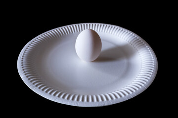 Egg on a white plate isolated on a black background