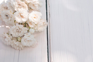 sprig of white small roses on white wooden background. Happy Birthday. Wedding invitation.