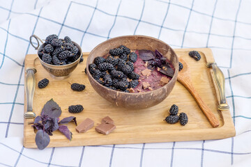 smoothie in a bowl of coconut with mulberry and chocolate
