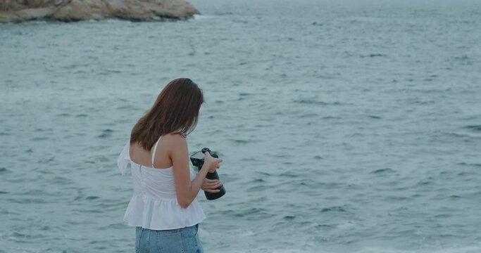 Woman use of digital camera to take photo of the sea